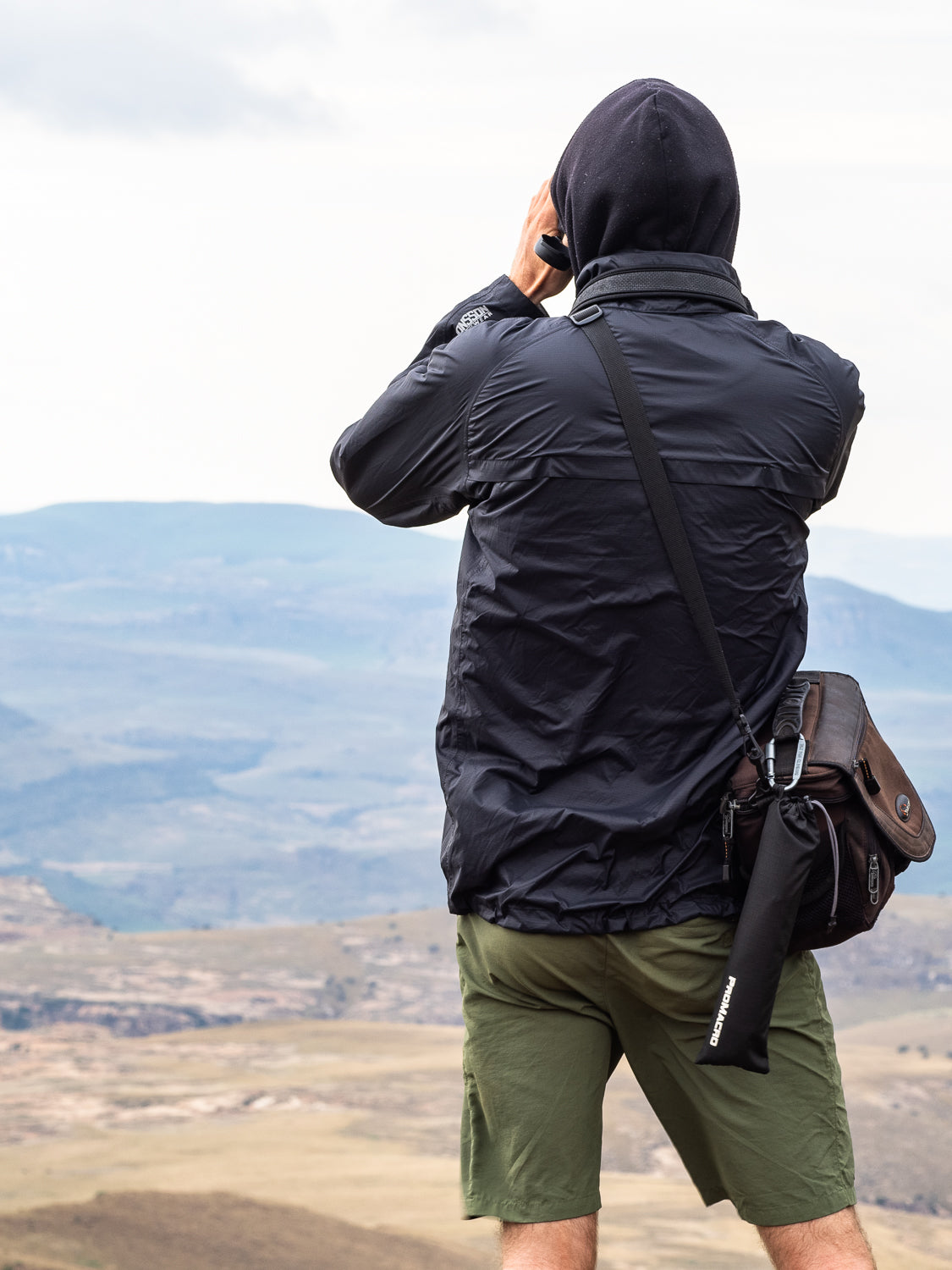 Photographer looking at landscape with ProMacro diffuser and camera bag.