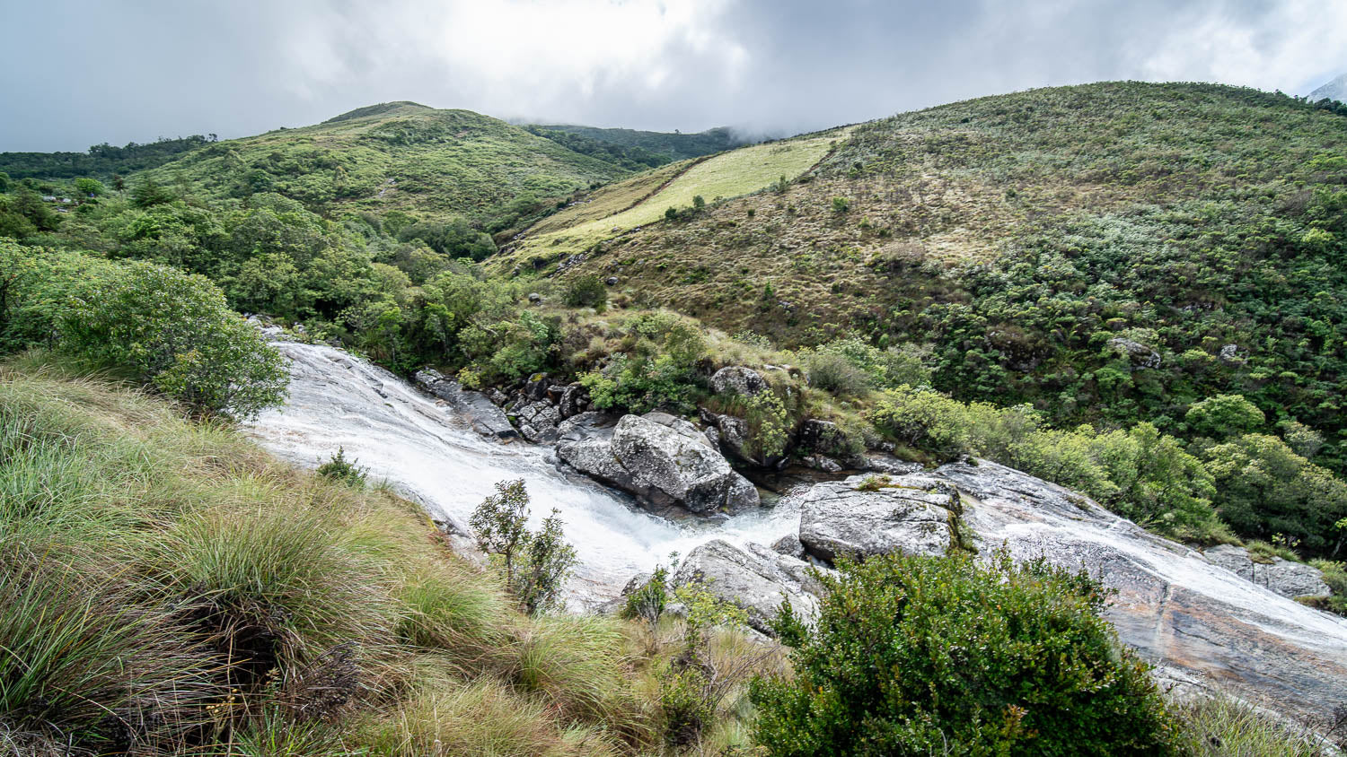 Scenic view of a river flowing through a hilly landscape with greenery.