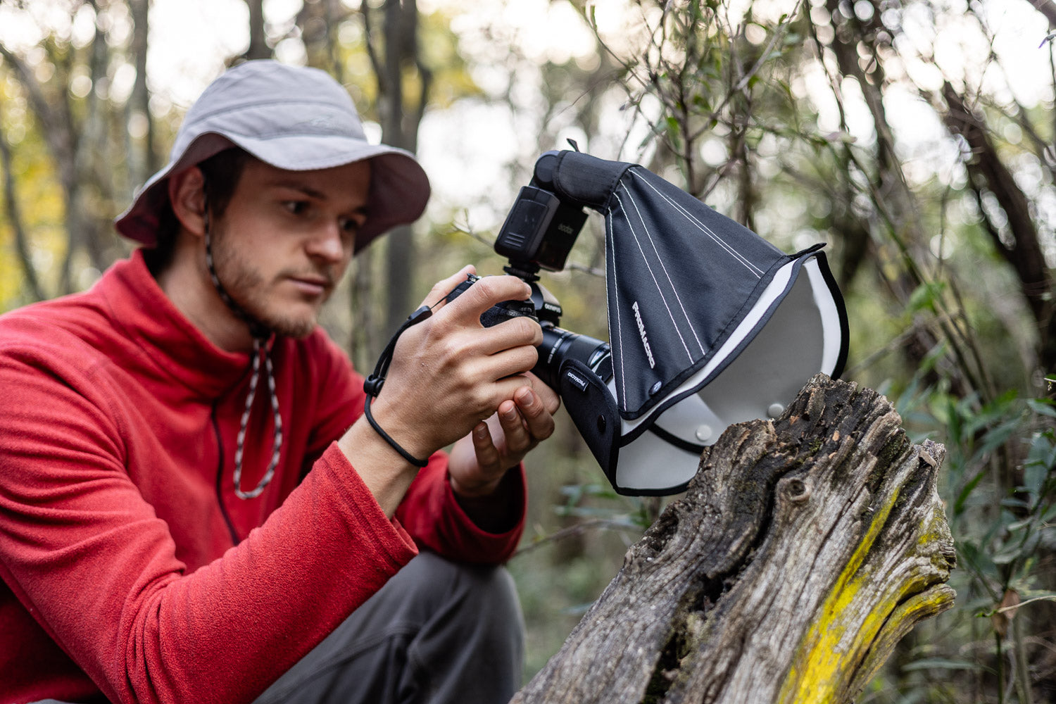 Person in a red jacket using a camera with a macro diffuser in a forest setting